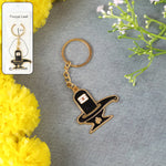 Golden Shivling keychain in metal with intricate design on plain background