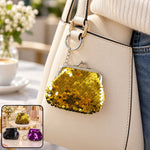 A gold sequined coin purse keychain hangs from a cream handbag, with an inset showing three color options on a vanity.