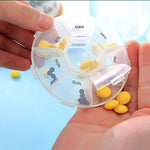 Hands holding a clear 7-day pill organizer with yellow and grey pills, dispensing yellow pills.