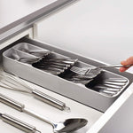 An empty, grey plastic cutlery tray with multiple compartments for kitchen drawer organisation.
