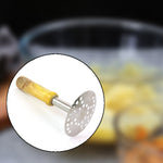 A circular inset shows the stainless steel masher with a wooden handle, superimposed over a blurred background of mashed