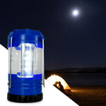 A blue and black LED lantern is in the foreground, with a glowing tent by a lake under a full moon in the background.