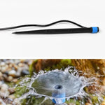 A black and blue water dripper with a thin black hose, with a close-up of the dripper spraying water in an outdoor setting.