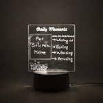 A clear acrylic message board lamp with glowing white text, set against a dark background.