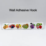 A white adhesive wall hook strip with fruit designs is centered on a plain white background with the text "Wall Adhesive
