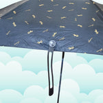 A close-up of the black umbrella canopy shows the gold musical note pattern and the handle's attachment point.