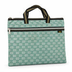 A green patterned document bag with black and gold striped handles and two zippered pockets, standing upright on a white