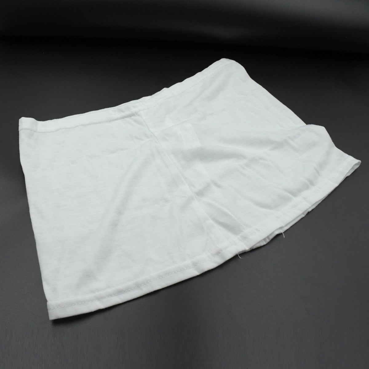A white layered hip skirt with shorts lies folded on a dark gray surface.