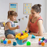 A young girl and an adult play with a blue and yellow shape sorter bucket and colorful blocks on a light-colored rug.