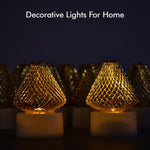 Close-up of several golden mesh LED tea lights with warm glow, against a dark background.