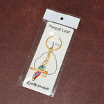 Side angle of Krishna flute keychain with peacock feather design in metal