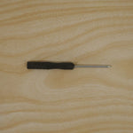 A black and silver mini screwdriver is centered on a light wooden surface.