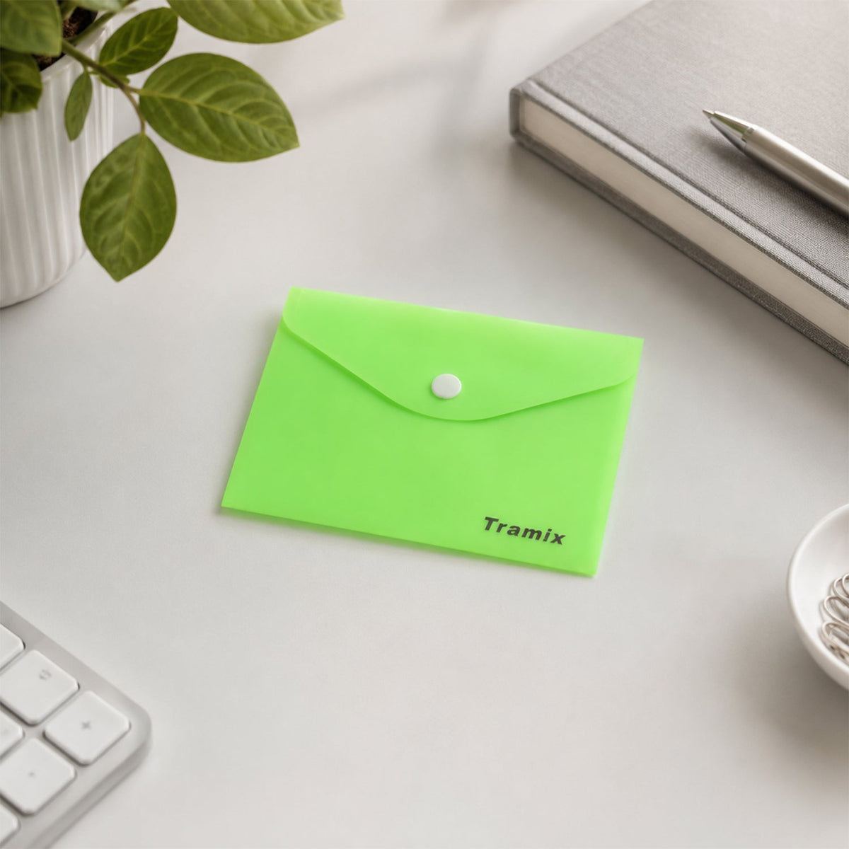 A closed neon green plastic document folder with a white button closure and "Tramix" printed on it, sits on a white desk