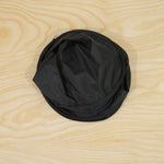 A single black car window sun shade folded into a compact, circular shape on a light wooden surface.