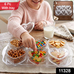 Six clear heart-shaped bowls with lids sit on a matching clear tray, filled with different colorful snacks on a wooden table.