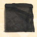 A folded black mesh zipper storage bag is laid flat on a light wood surface.