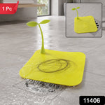 A bright yellow square silicone drain cover with a green sprout-like handle, collecting hair on a wet floor.