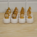 Twelve golden lantern LED candles with white bases are neatly packaged in a clear plastic tray on a light wooden surface.