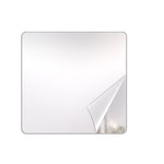 A square mirror with rounded corners has a corner of its protective film peeled back, revealing a reflection.