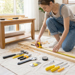 A person in denim overalls measures a wooden board with a yellow tape measure, surrounded by various hand tools.