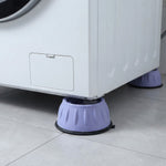 Two purple anti-vibration pads supporting the front and back corners of a white washing machine on a tiled floor.