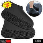 A person's feet wearing black silicone shoe covers stand on a wet wooden deck.