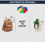The DrizzlePro umbrella is shown above a backpack and a tote bag, illustrating its compact portability when folded.