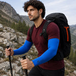 A man hiking on a rocky trail wears blue arm sleeves, a maroon t-shirt, and a black backpack. – view 8