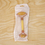 Dual-ended yellow jade facial roller in its clear plastic packaging