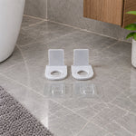 Two white plastic bottle holders with clear adhesive pads on a pure white background.