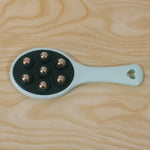 Handheld roller ball massager in retail packaging.