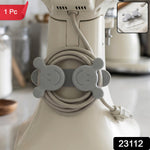 A gray silicone cord organizer with two smiling faces, holding a coiled light gray appliance cord on a white stand mixer,