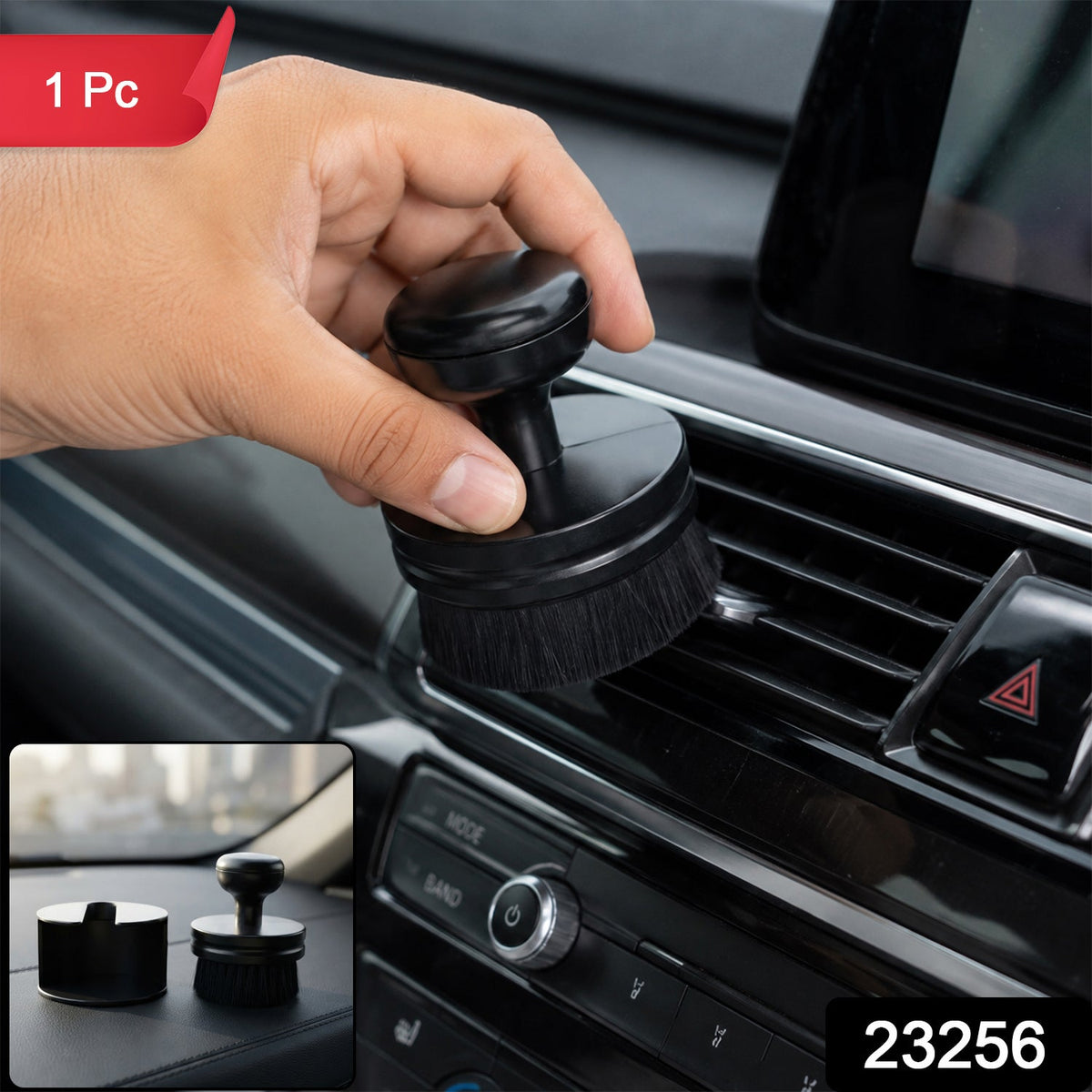 A hand holds a black detailing brush, cleaning a car's air vent, with a small inset showing the brush and its base – view 2
