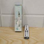 The multi-tool cleaning pen next to its light blue and white retail packaging on a wooden surface.