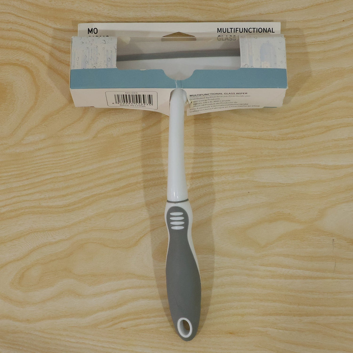 A white and gray glass wiper in its packaging, displayed on a light wooden surface.