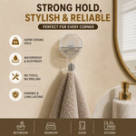 A clear self-adhesive hook holds a beige towel on a light tiled wall, with icons indicating its features and uses.