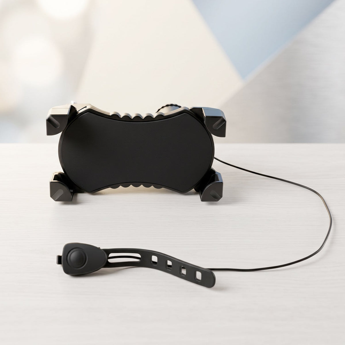A black bicycle phone holder and a separate horn with a strap are displayed on a light wooden surface.