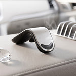 A hand holds a smartphone displaying a map application, attached to the car air vent holder.
