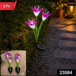 A single purple and white solar flower stake light illuminates a garden pathway at dusk, with '2 Pc' and '23584' labels.
