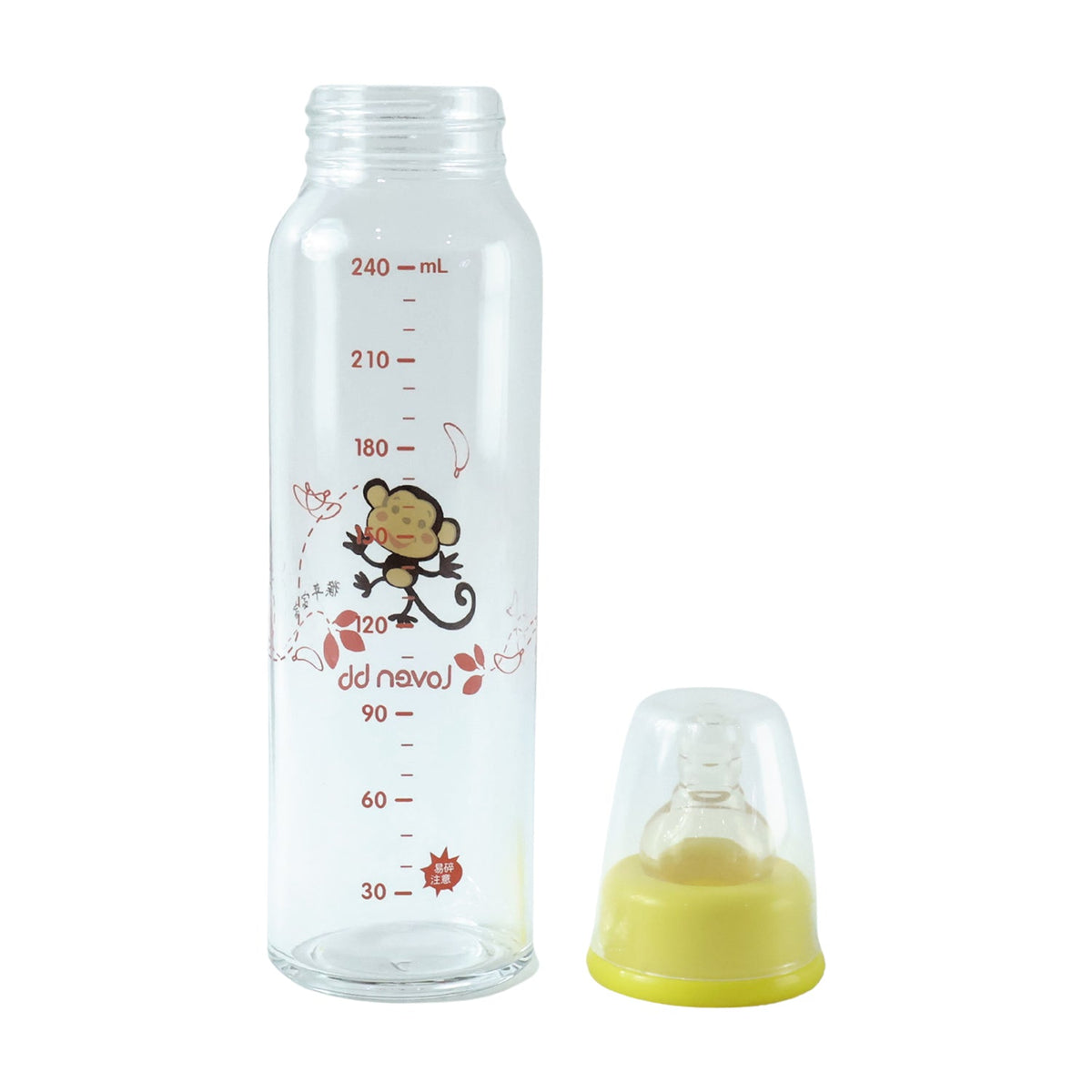 A clear glass baby bottle with a monkey design and a separate yellow nipple with clear cap are on a white background.
