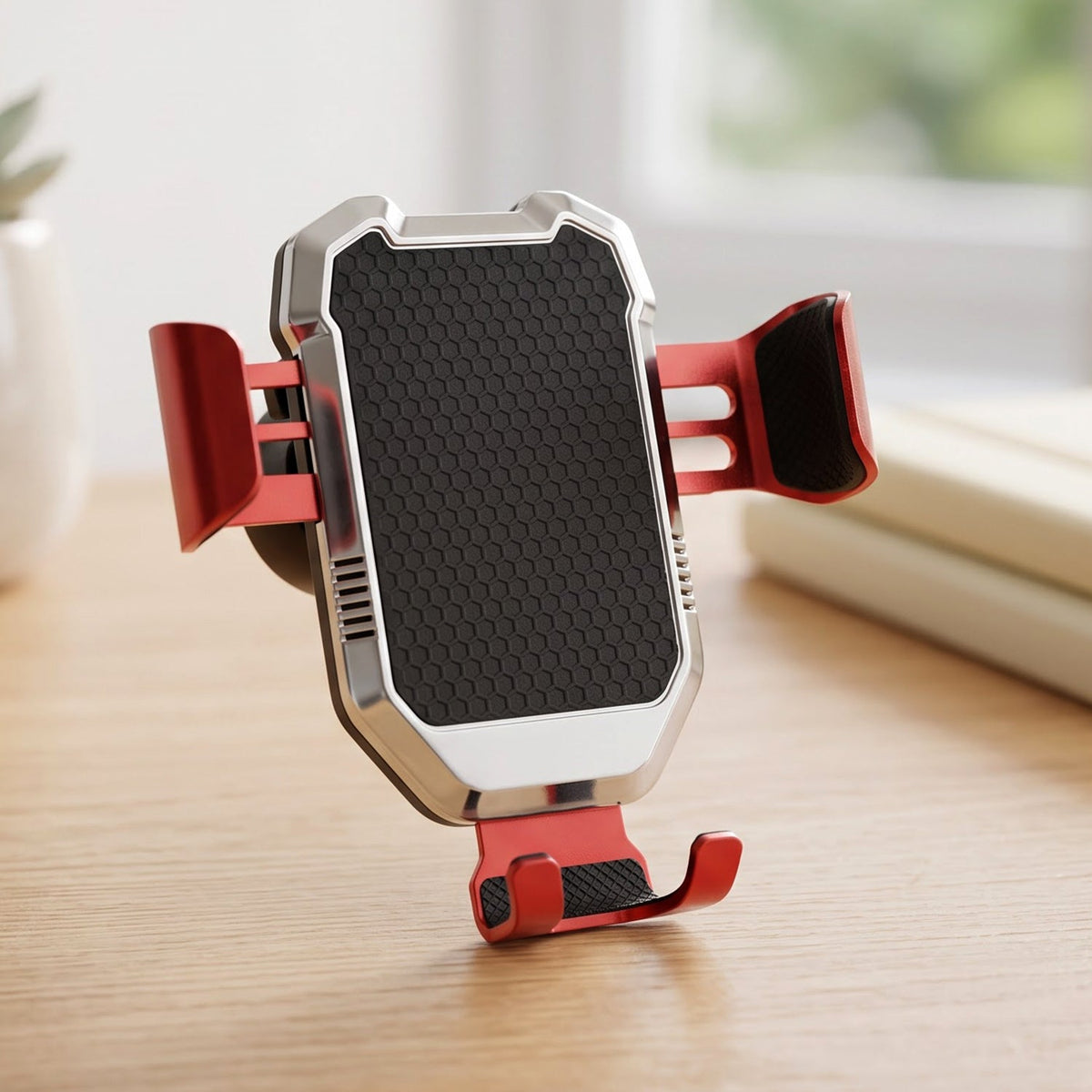 A red and silver car phone holder with a black textured grip stands upright on a light wooden surface.