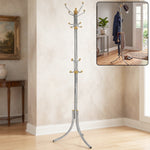 A tall, silver-colored metal clothes hanger stand with gold accents and multiple hooks stands in a room with a painting and