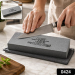 A gray silicon carbide whetstone with black text rests on a gray towel on a white marble counter.