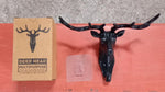 Three deer head wall hooks in black, white, and grey mounted on a wall.