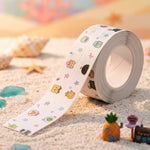A roll of white cartoon-printed sealing tape unrolling onto sand with seashells and small decorative items.