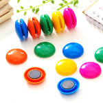 Circular board magnets in assorted colors displayed on a surface.