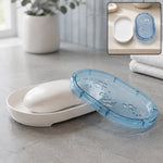 White soap dish with a bar of white soap and a translucent blue lid with butterfly cutouts, in a bathroom setting