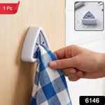 A hand inserts a blue and white checkered towel into a white and grey triangular wall-mounted towel holder onlight wooden