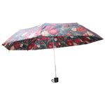 A fully open floral umbrella, featuring red and white flowers on a dark green canopy, is displayed against a plain white