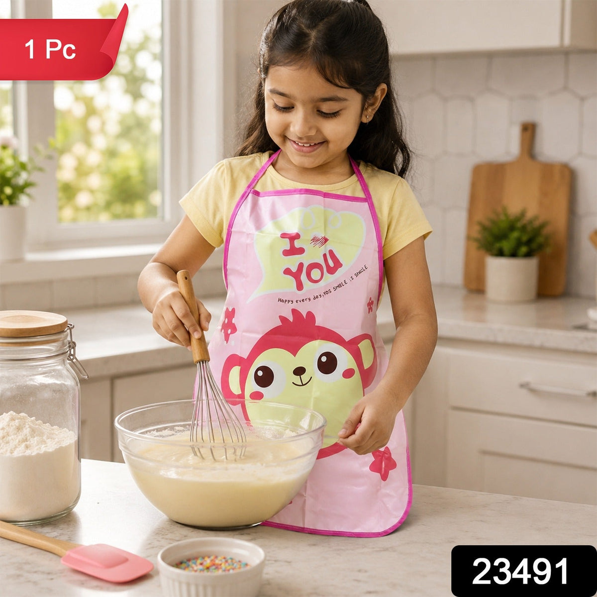 A young girl in a pink monkey apron smiles while whisking batter in a glass bowl in a kitchen, with a red "1 Pc" label and a